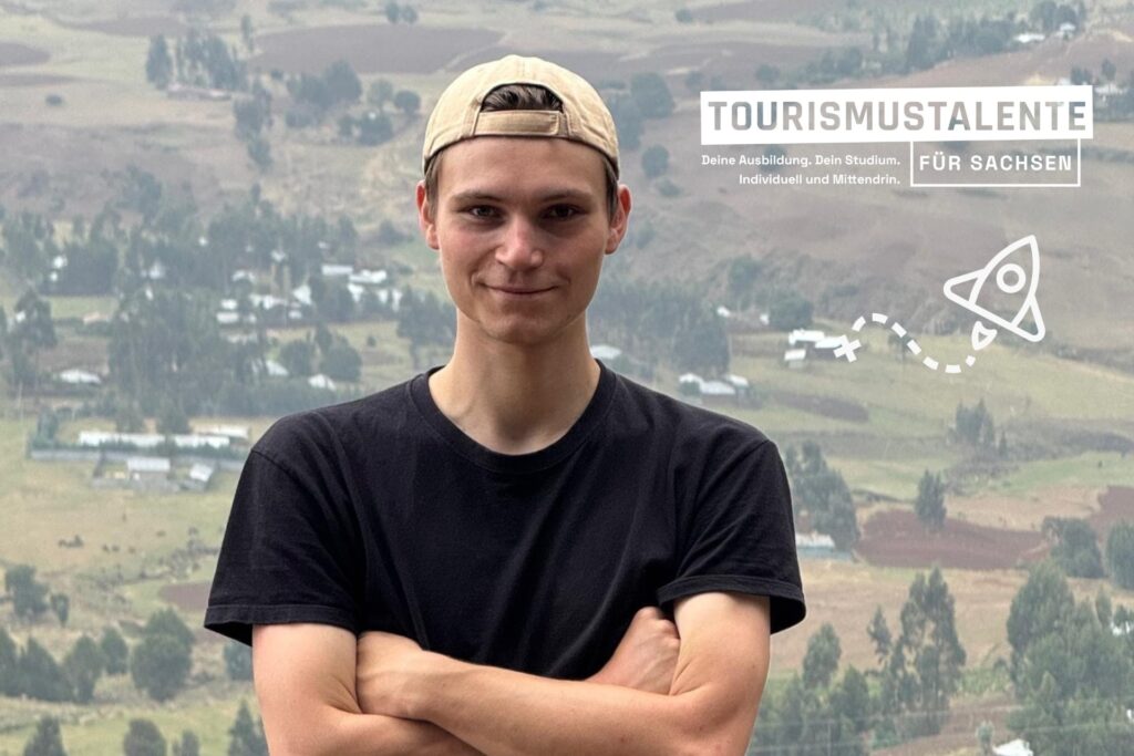 Ein junger Mann mit verschränkten Armen lächelt